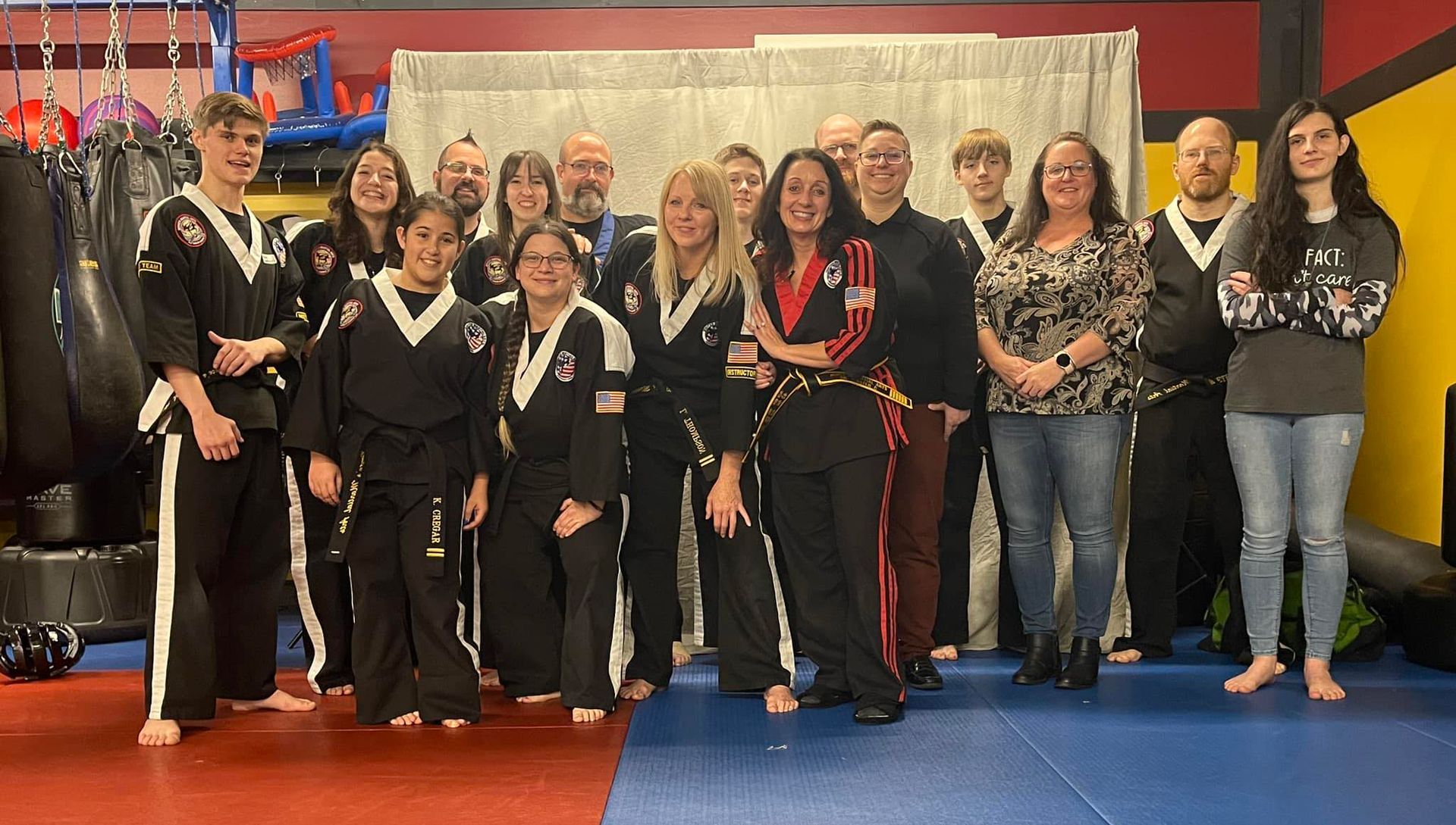 a group of people in martial arts uniforms are posing for a picture in a gym .