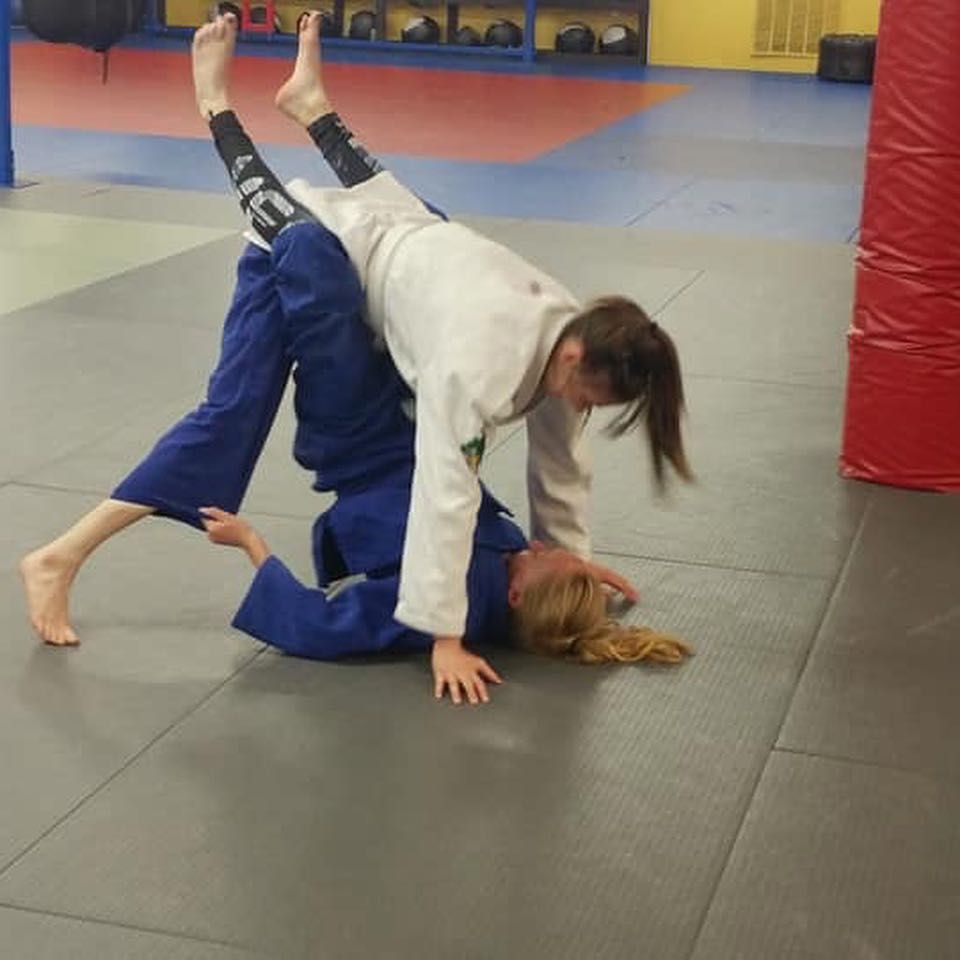 two women are practicing judo on a mat in a gym .
