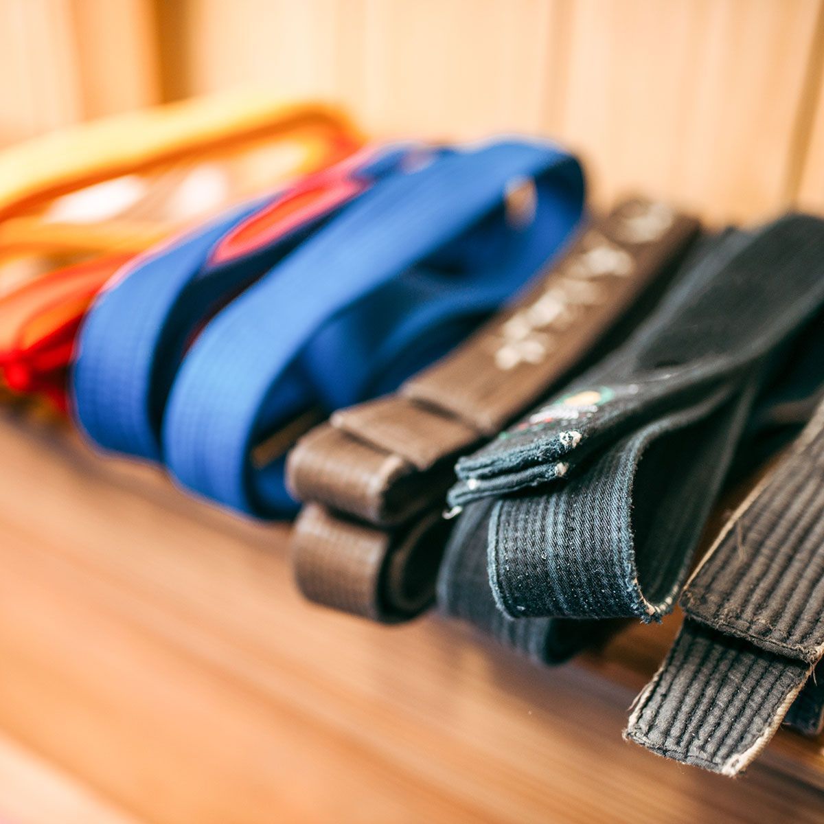 a row of karate belts are stacked on top of each other on a wooden shelf .