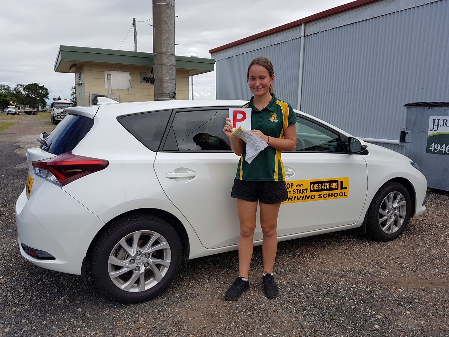 Young Person Holding a License Next to a White Car — Top Start Driving School (Whitsunday) In Airlie Beach, QLD