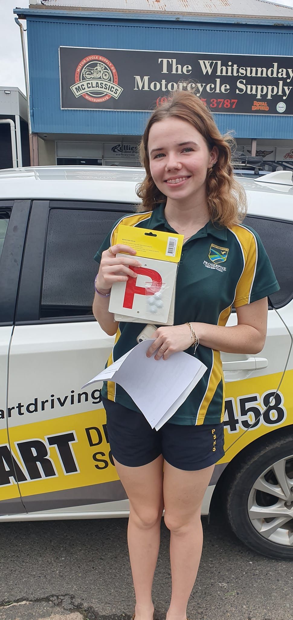 Young Person Holds a  a License Next to a White Car — Top Start Driving School (Whitsunday) In Airlie Beach, QLD