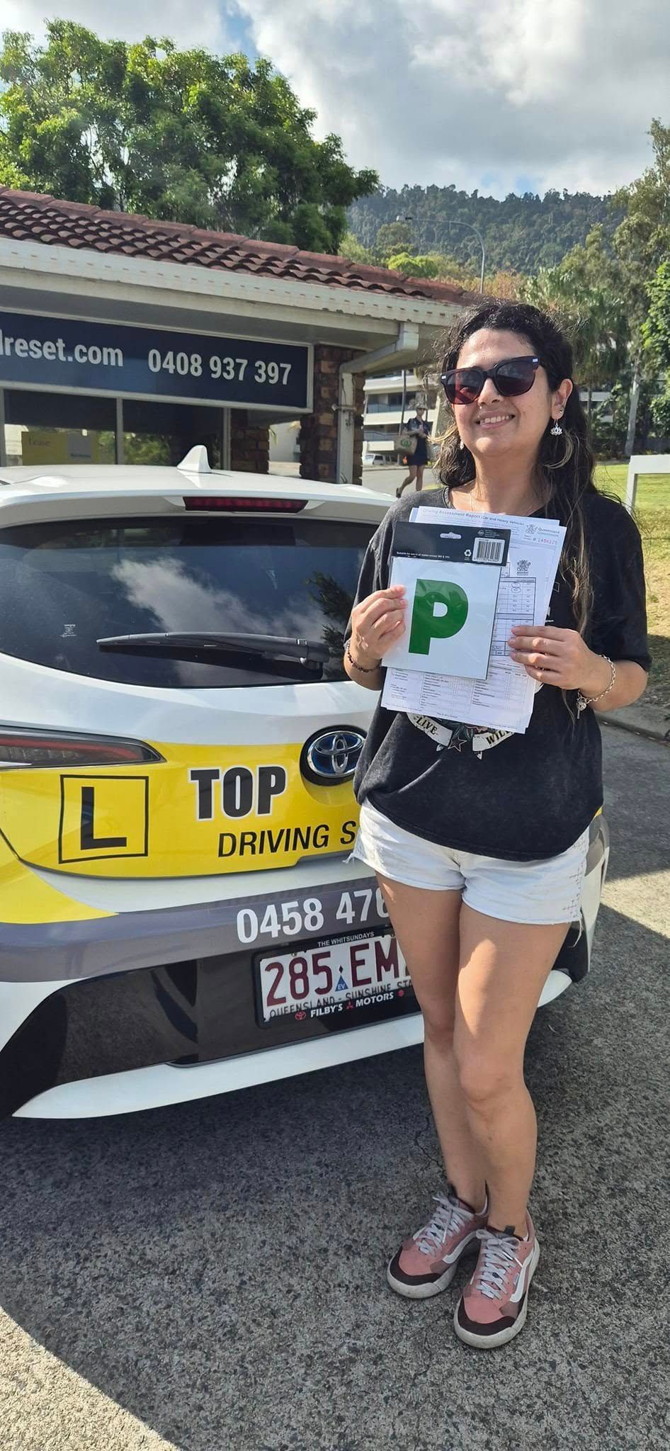 Woman Holding a P-plate Next to a Car — Top Start Driving School (Whitsunday) In Airlie Beach, QLD
