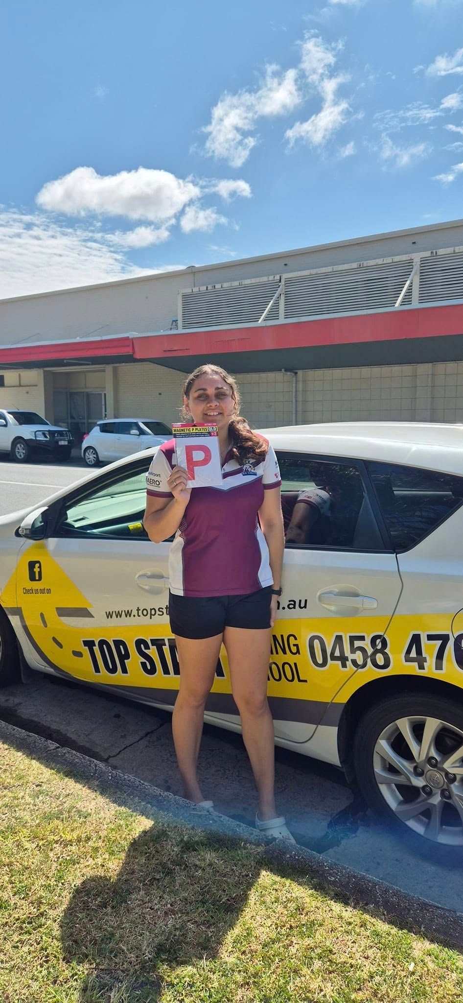 Person Holding a P Plate in Front of a Driving School Car — Top Start Driving School (Whitsunday) In Airlie Beach, QLD