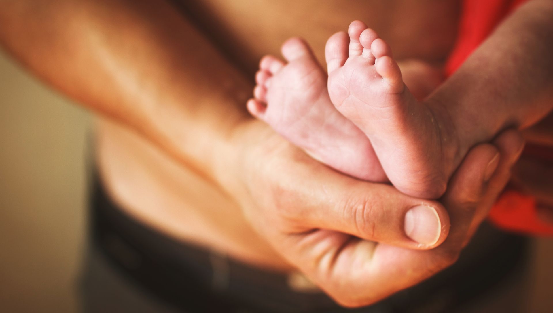 A man is holding a baby 's feet in his hands.