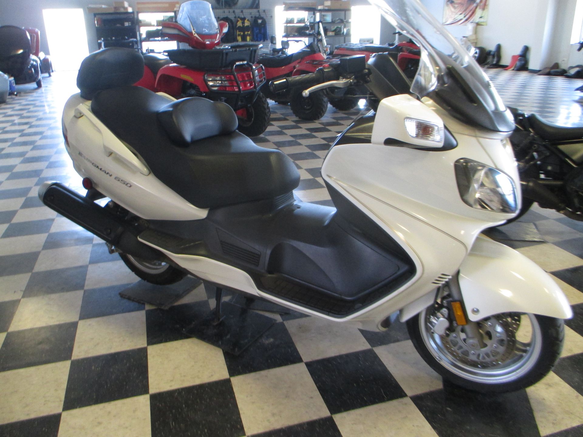 A white scooter is parked on a checkered floor