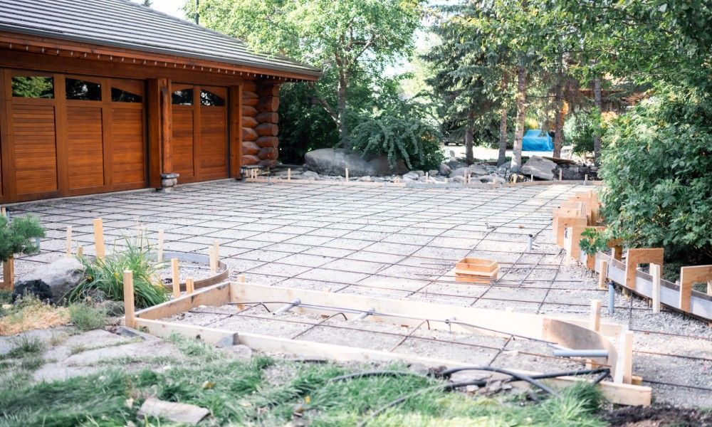 The installation process for a concrete driveway. The concrete rebar is exposed atop a layer of grav