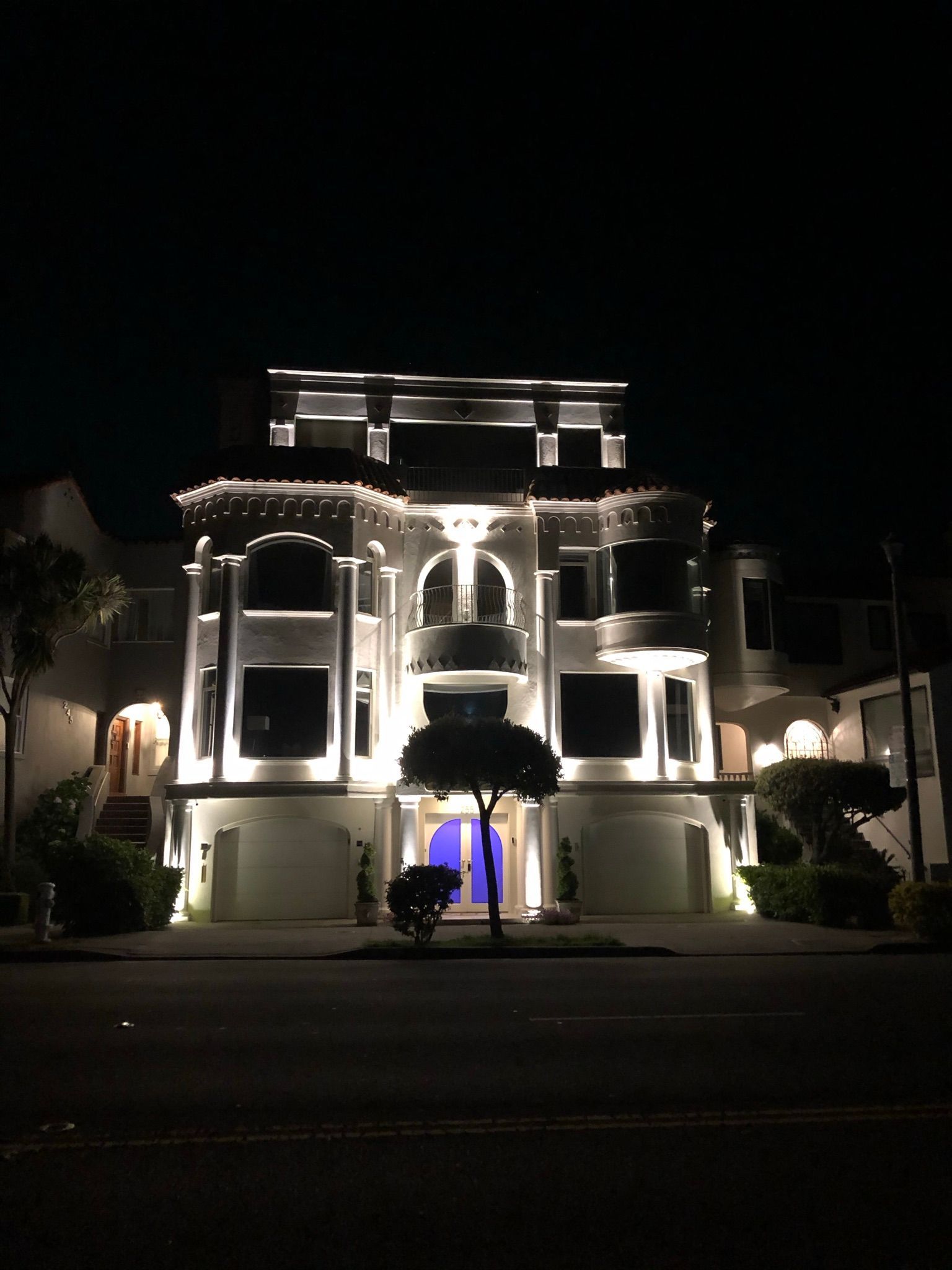 A large white house is lit up at night.