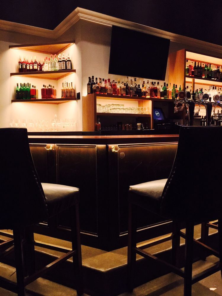 A bar with two chairs and bottles on shelves