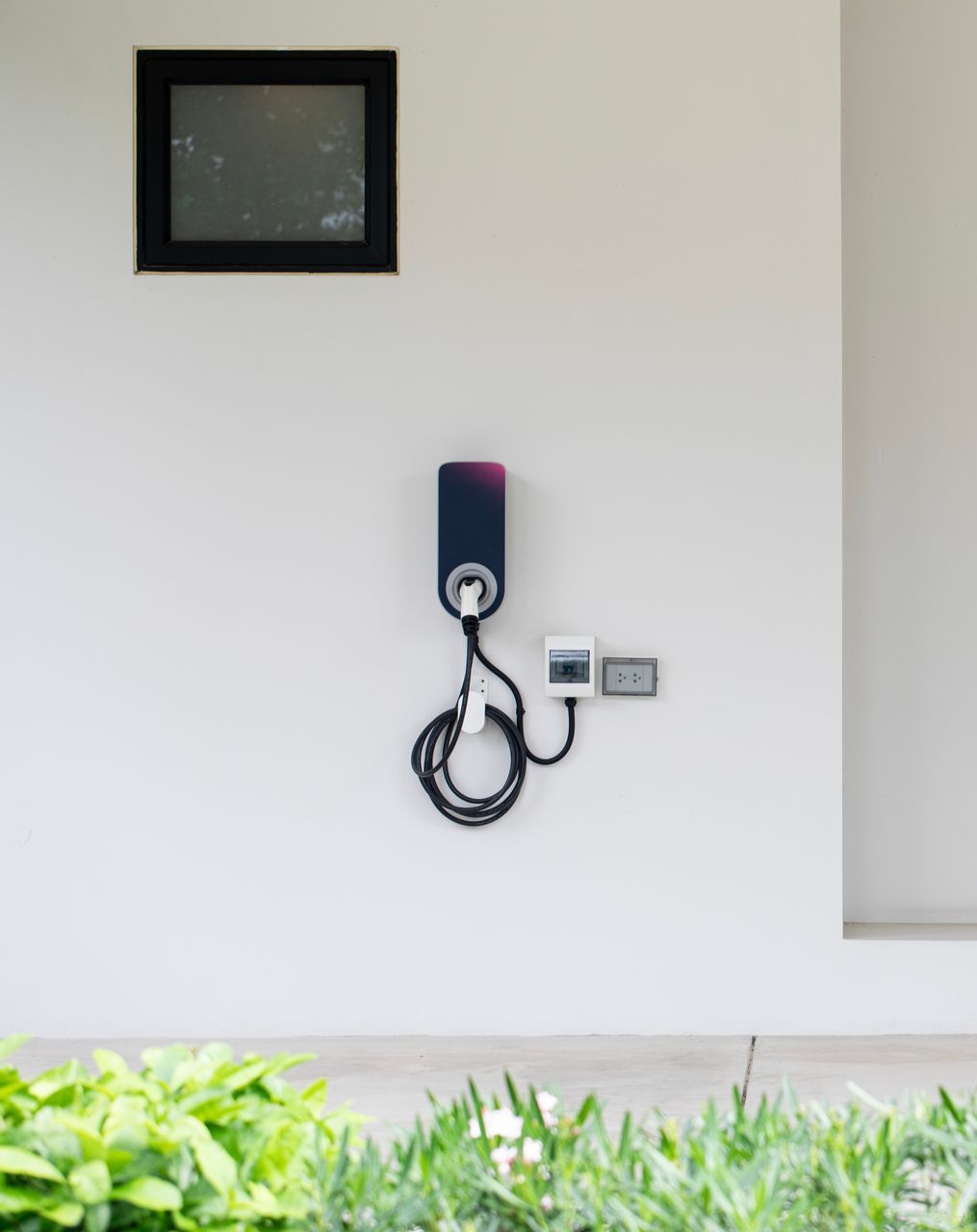 An electric car charger is mounted to a white wall