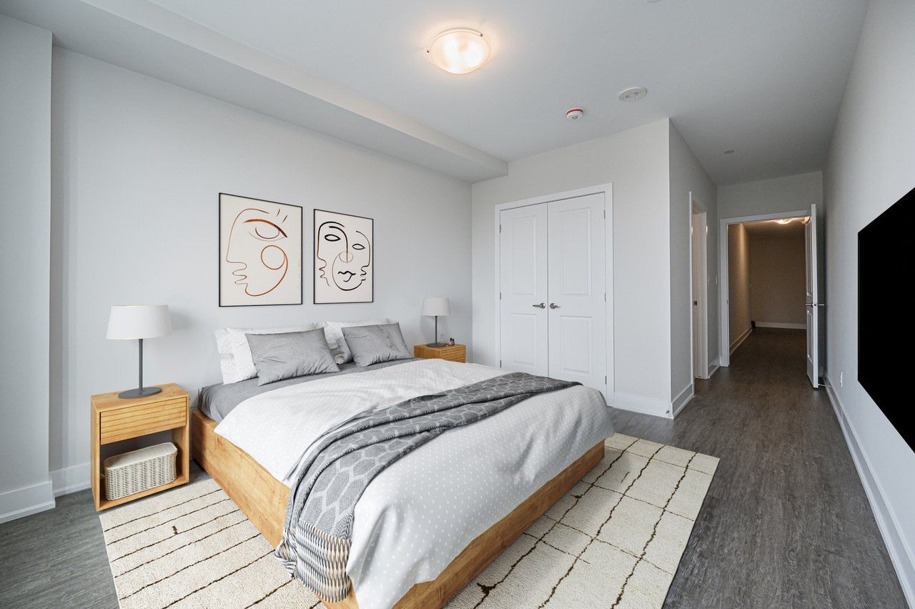 A bedroom with a large bed , two nightstands , a rug and a television.