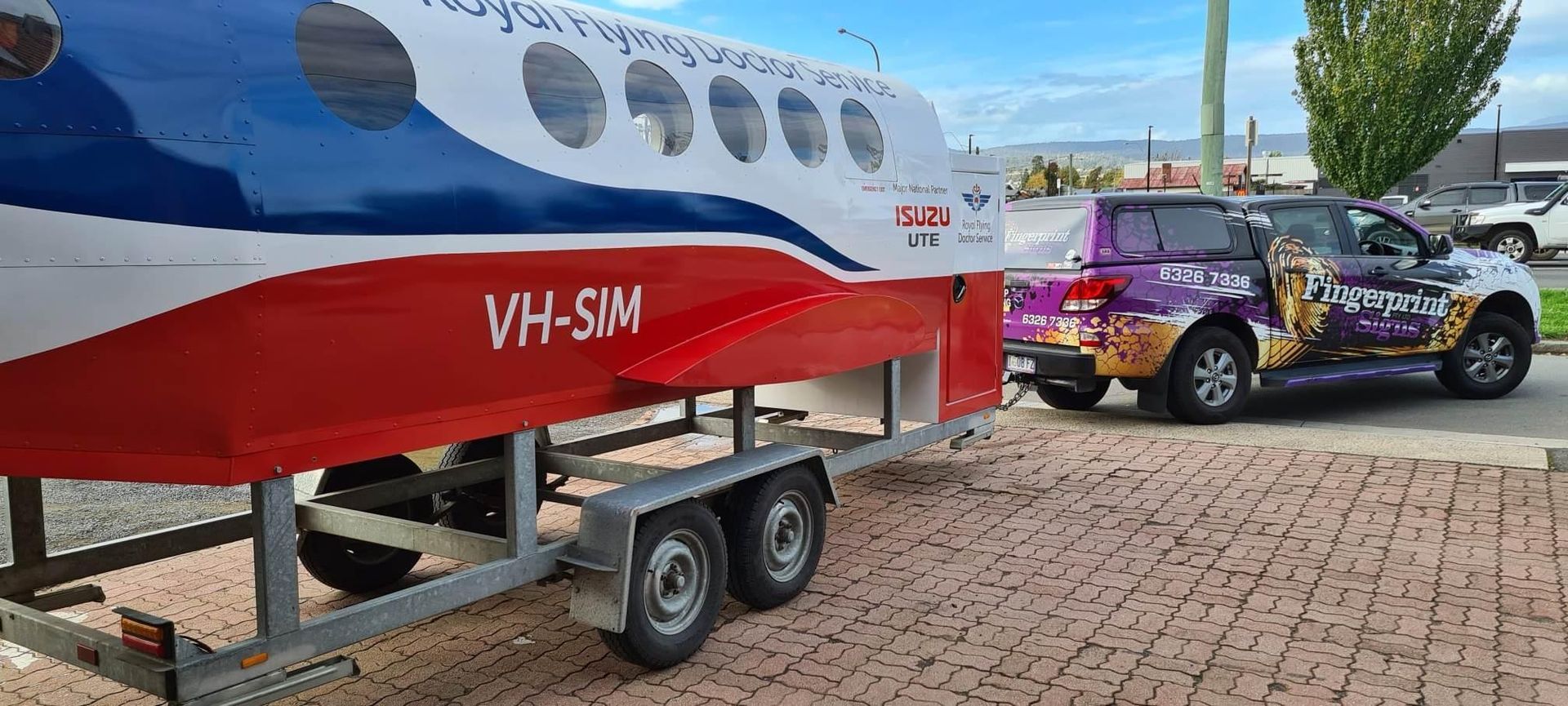 A red , white and blue airplane is on a trailer next to a truck.