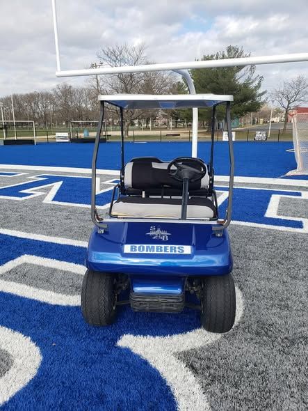 Blue golf cart on a blue and gray football field with 