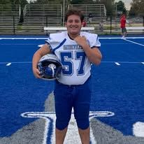 Football player in a blue uniform holding a helmet on a blue field.