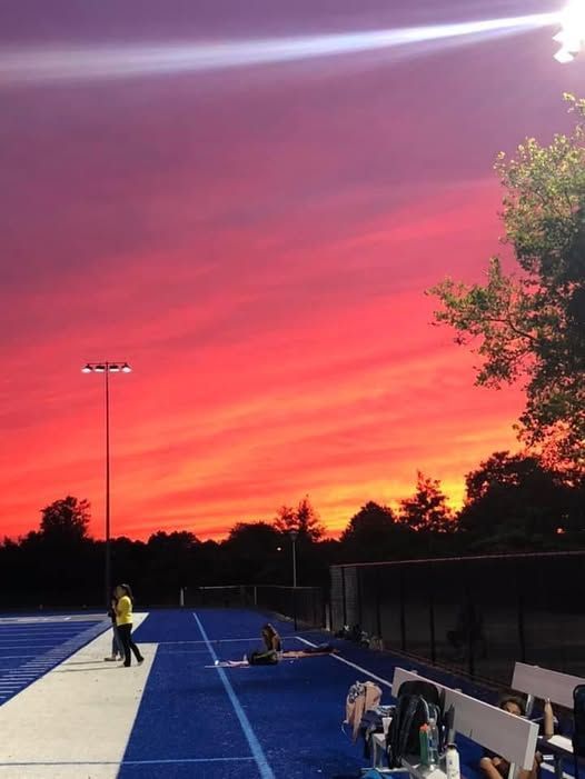 Athletic track under a vibrant red and orange sunset. People are present.