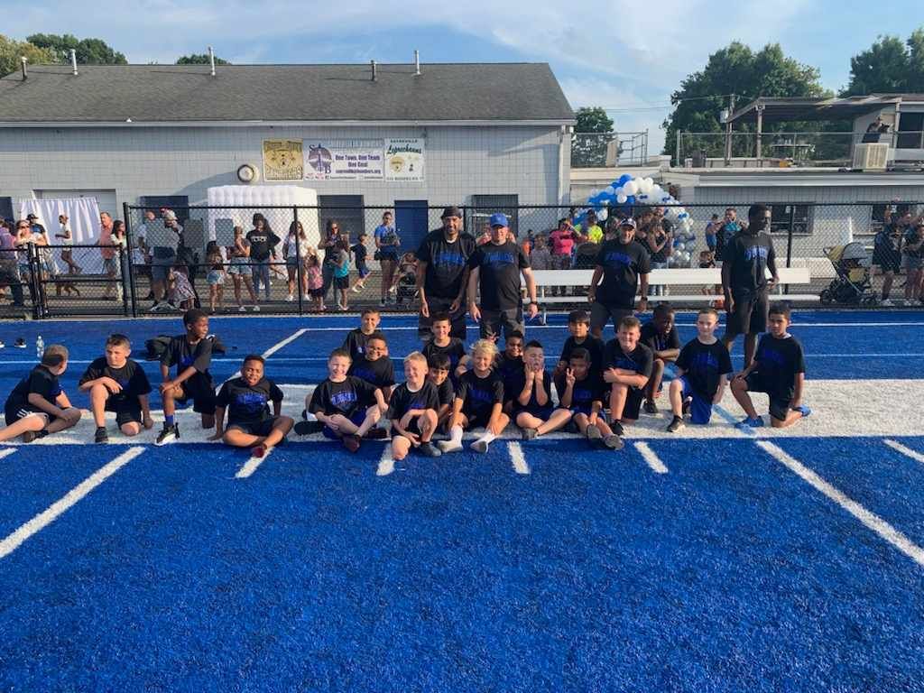Group of kids in blue track uniforms on a blue track, posing for a photo.