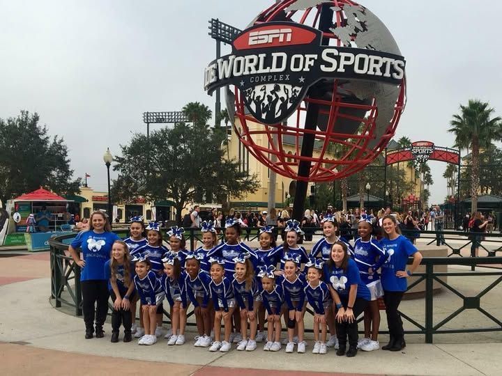 Cheerleading team in blue and white uniforms in front of the ESPN World of Sports Complex globe.