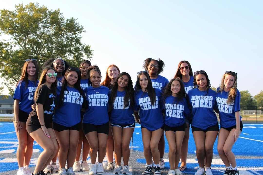 Group of cheerleaders in blue shirts and black shorts on a blue track.
