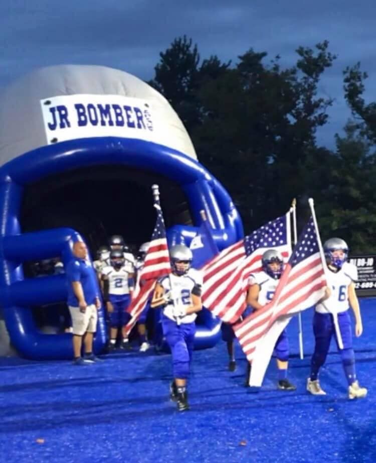 Football players in blue uniforms exit a tunnel with 