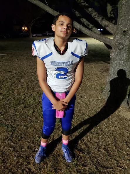 Football player in blue and white uniform, number 2. Outdoors, holding pink object.