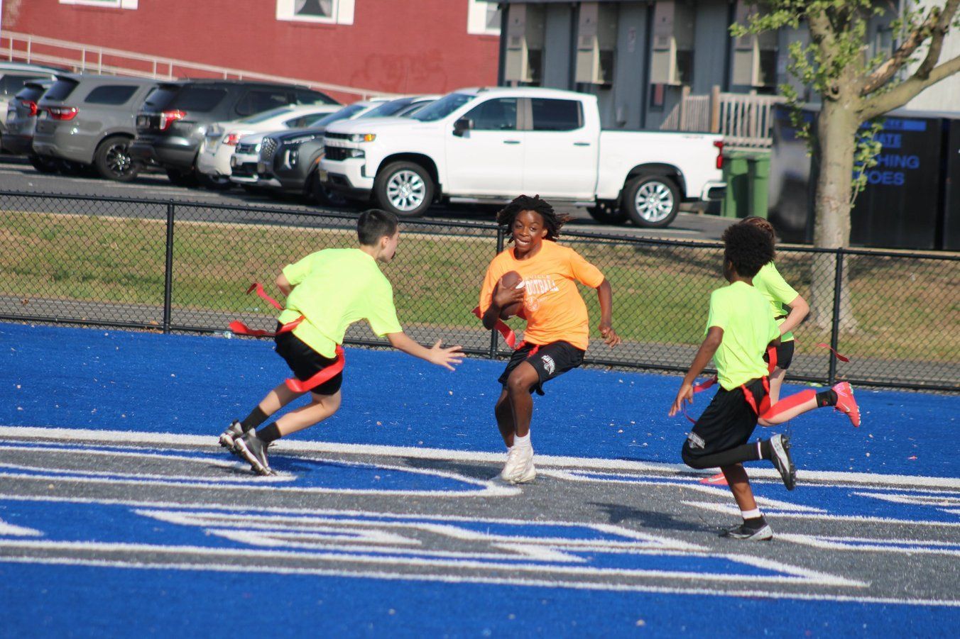 Football player in silver uniform runs with ball on a green field.