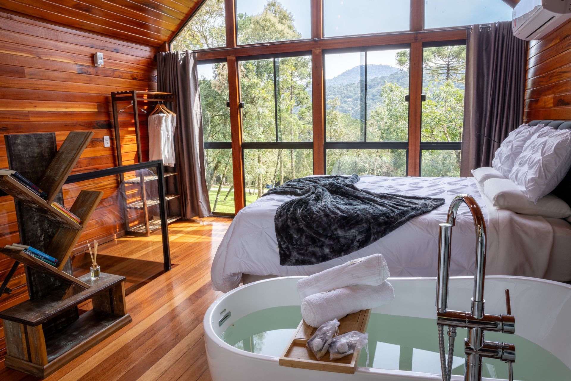 Quarto em cabana de madeira com vista, equipado com banheira, cama e guarda-roupa.