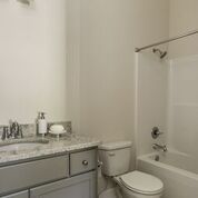 Bathroom with a white toilet, bathtub, and gray vanity with a granite countertop.