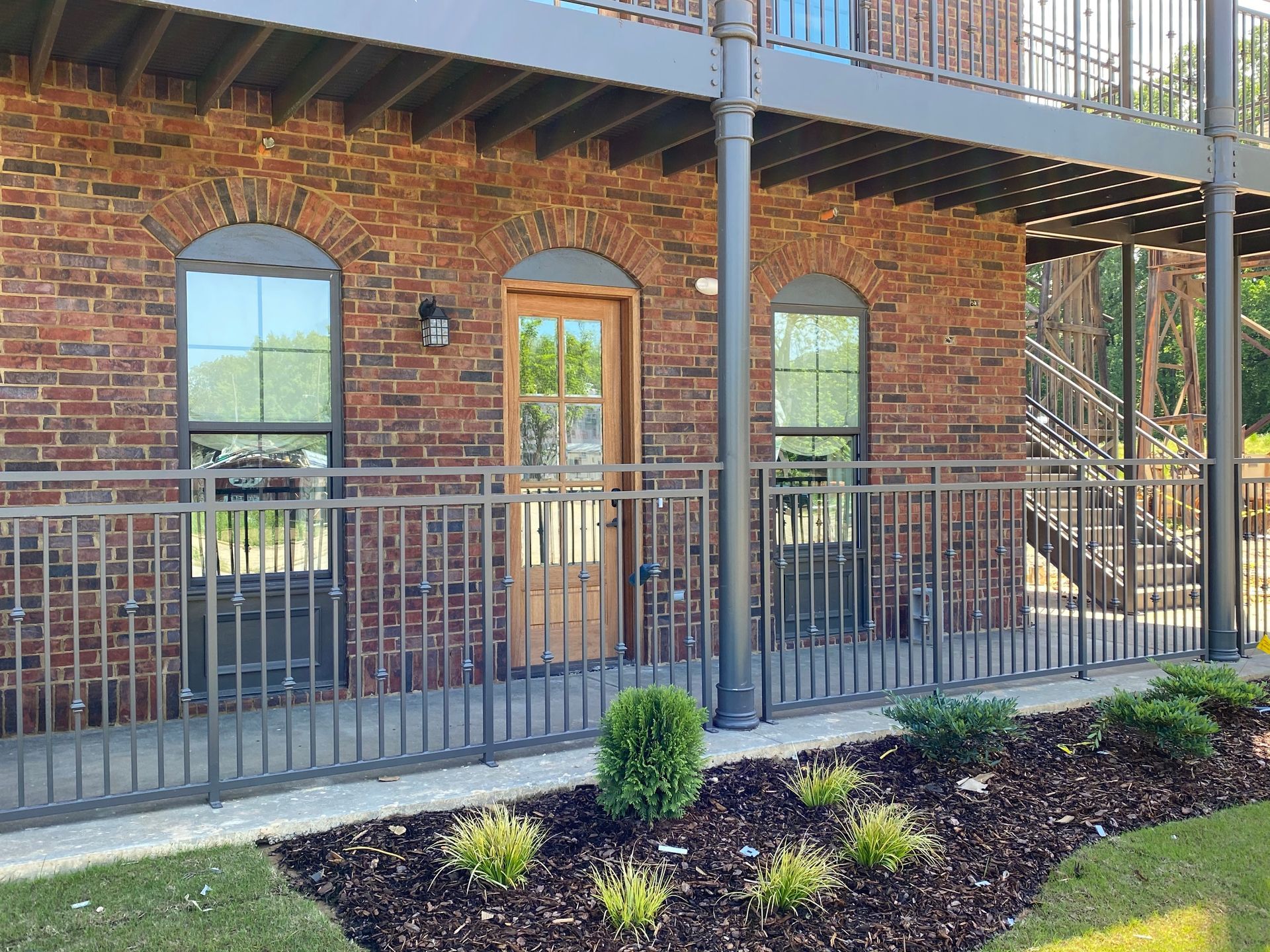 Brick building with iron railings, wooden door, and landscaped garden.
