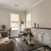 Living room with tan walls, white trim, and distressed white cabinet, with coffee table and seating.