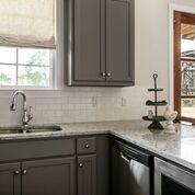 Kitchen with gray cabinets, white countertops, a window, and a stainless steel sink.
