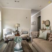 Living room with two armchairs, a sofa, coffee table, lamps, and decor. Beige and gray color scheme.