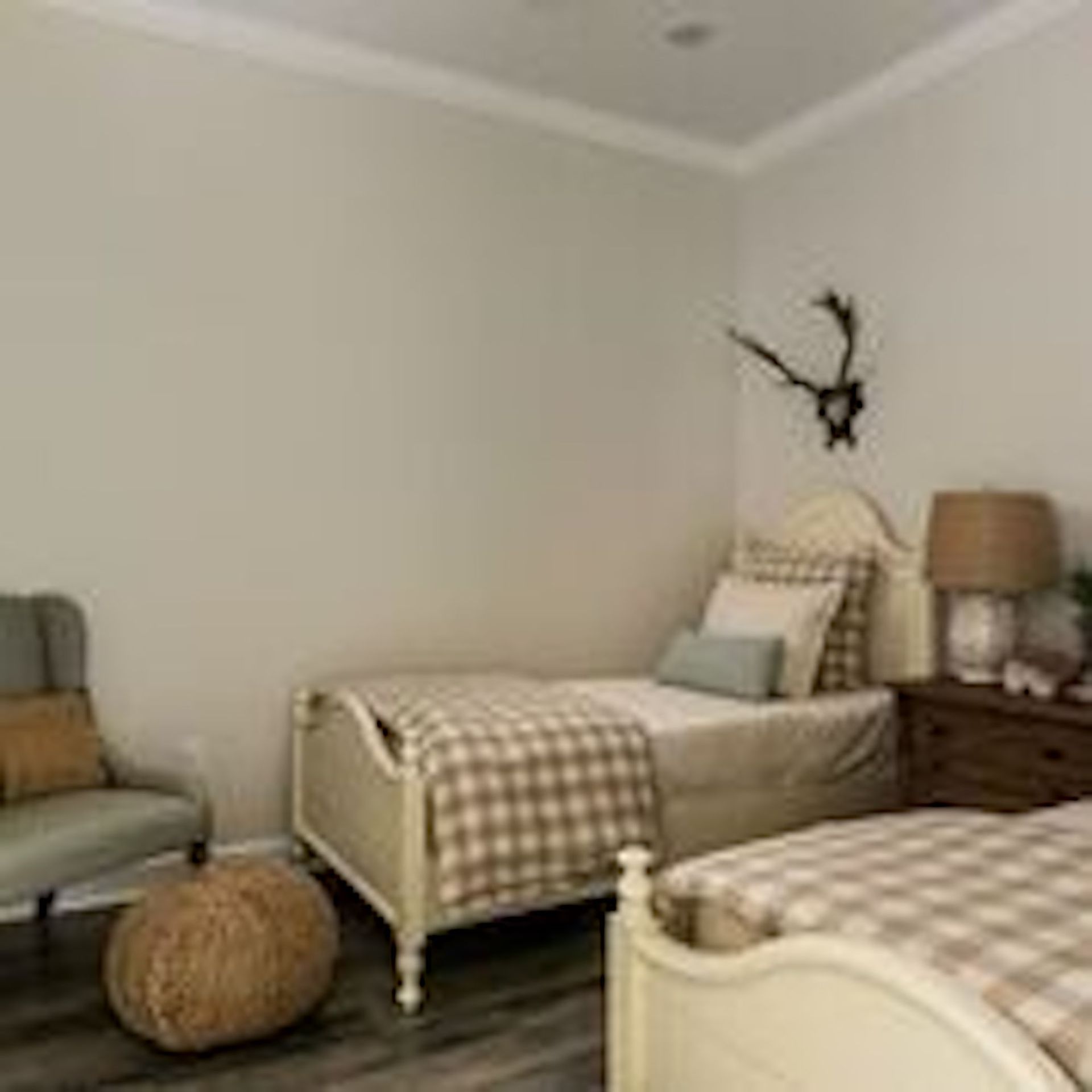 Bedroom with two twin beds, chair, and a decorative antler mount.