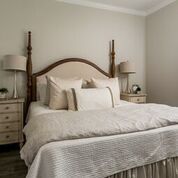 Bedroom with a four-poster bed, nightstands, lamps, and neutral-toned bedding.
