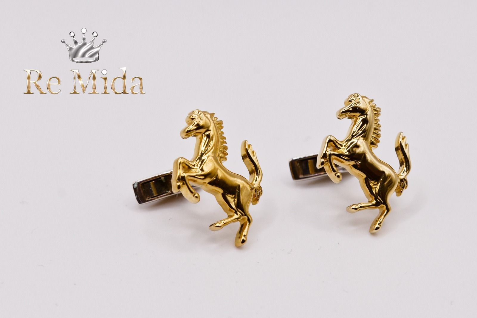 Gemelli color oro a forma di cavalli rampanti, su una superficie bianca.