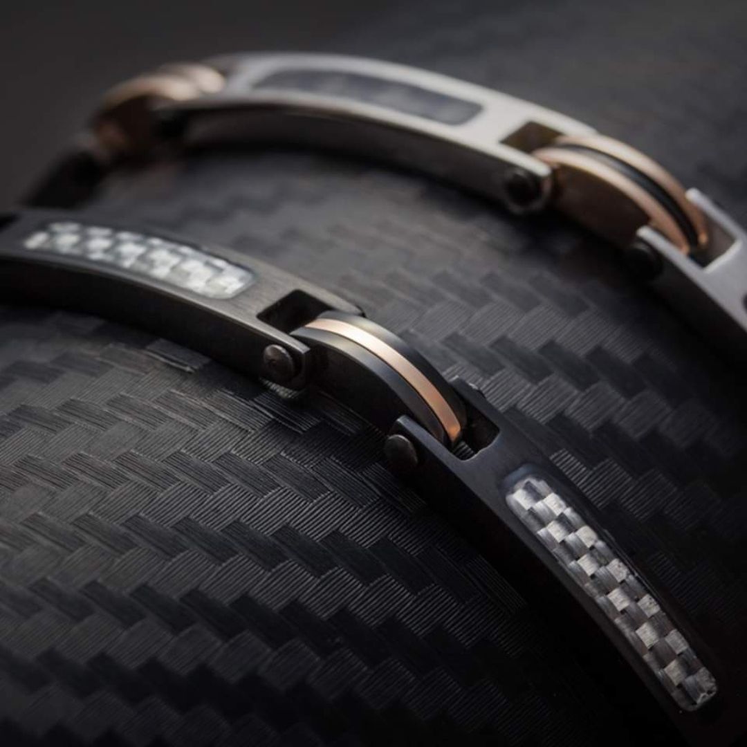 Primo piano di due bracciali collegati, uno nero e uno argentato, montati su fibra di carbonio.