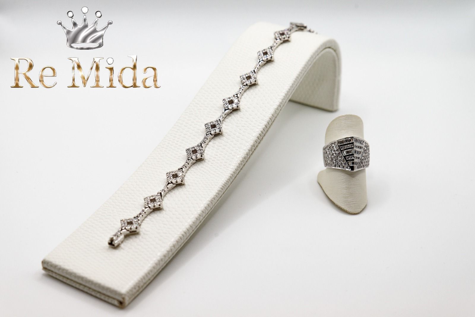 Bracciale e anello con gemme trasparenti su sfondo bianco. Logo 