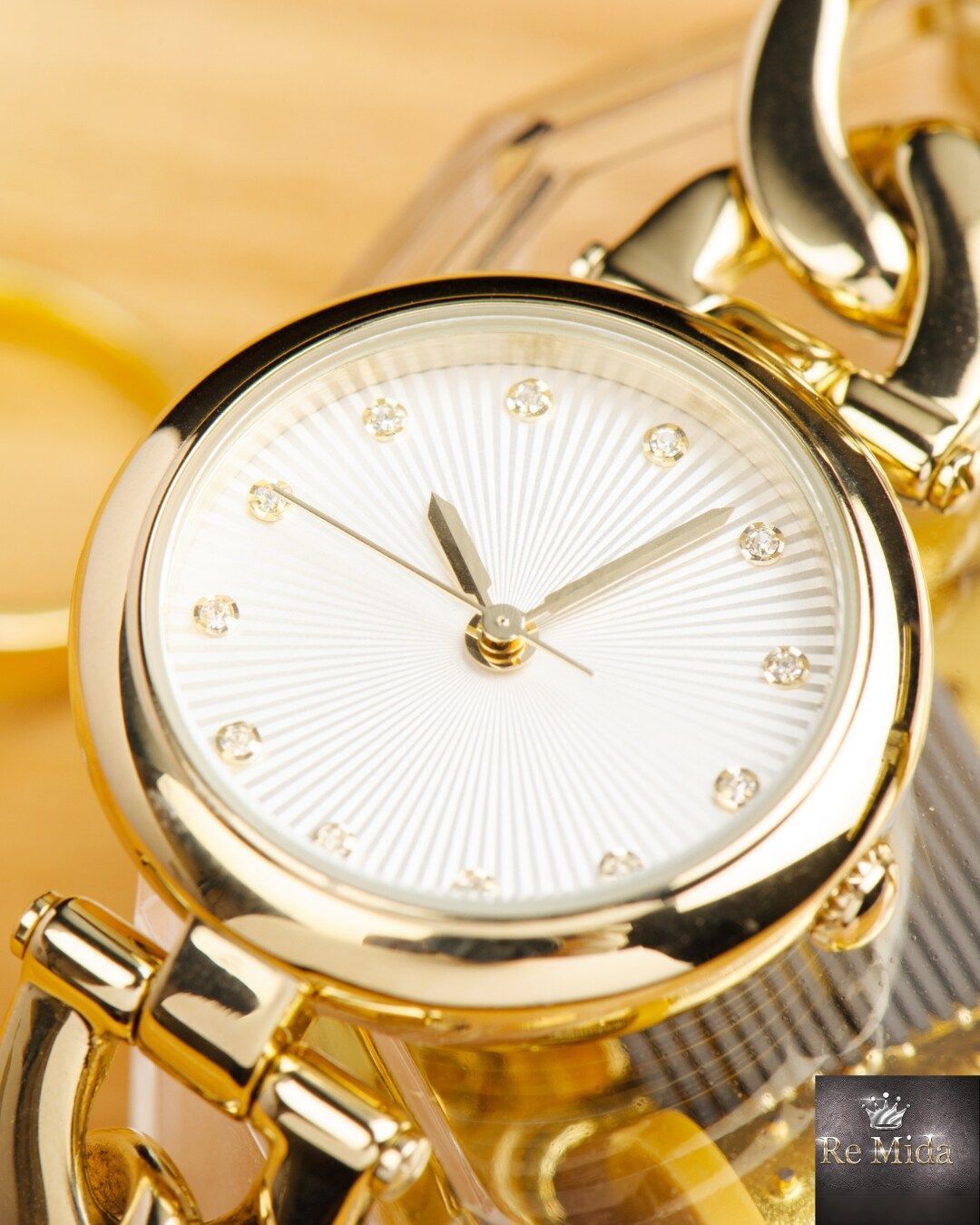 Orologio da polso in oro con quadrante bianco e indici di diamanti, cinturino a catena in oro.