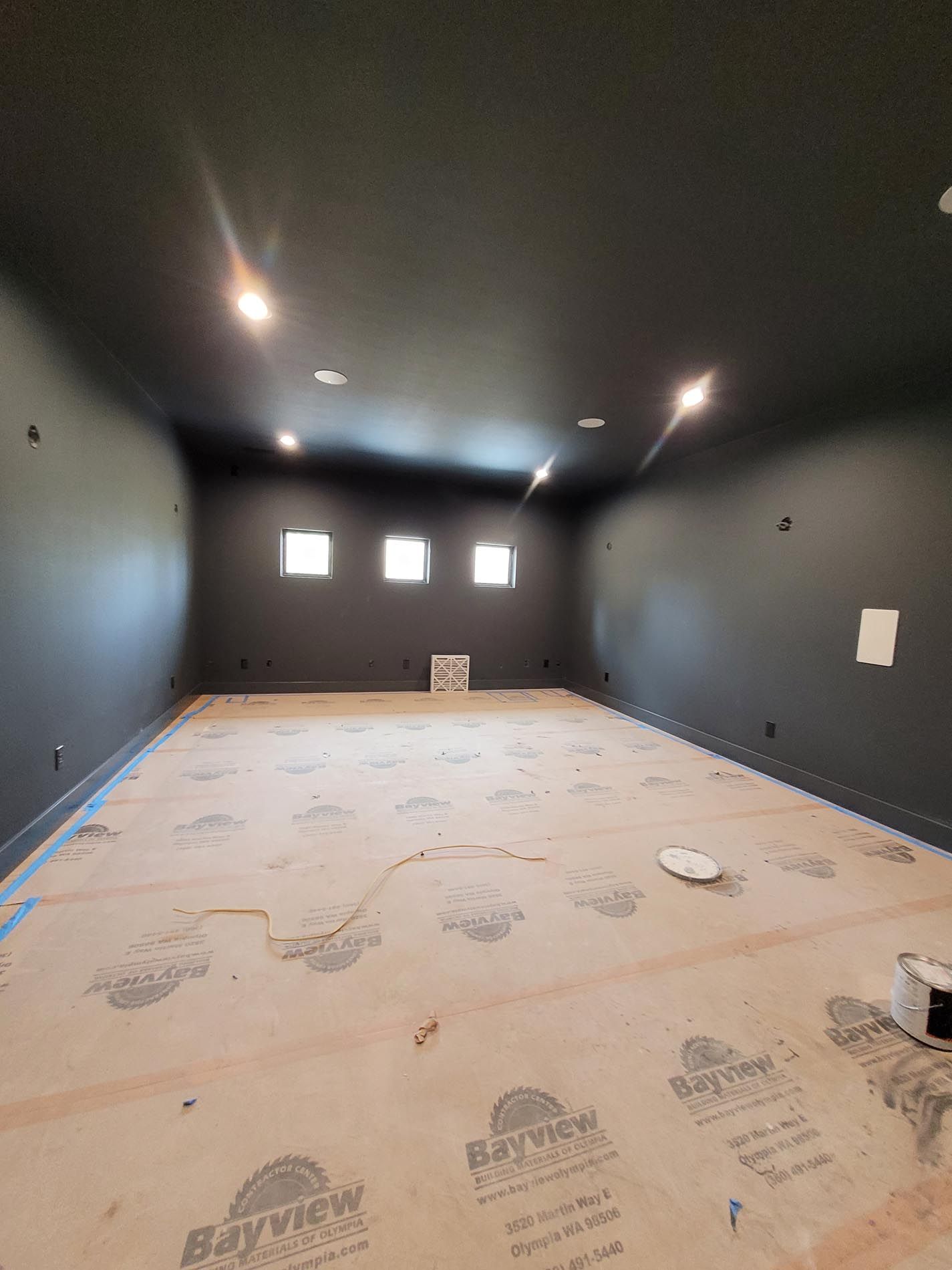 A large empty room with black walls and a wooden floor.