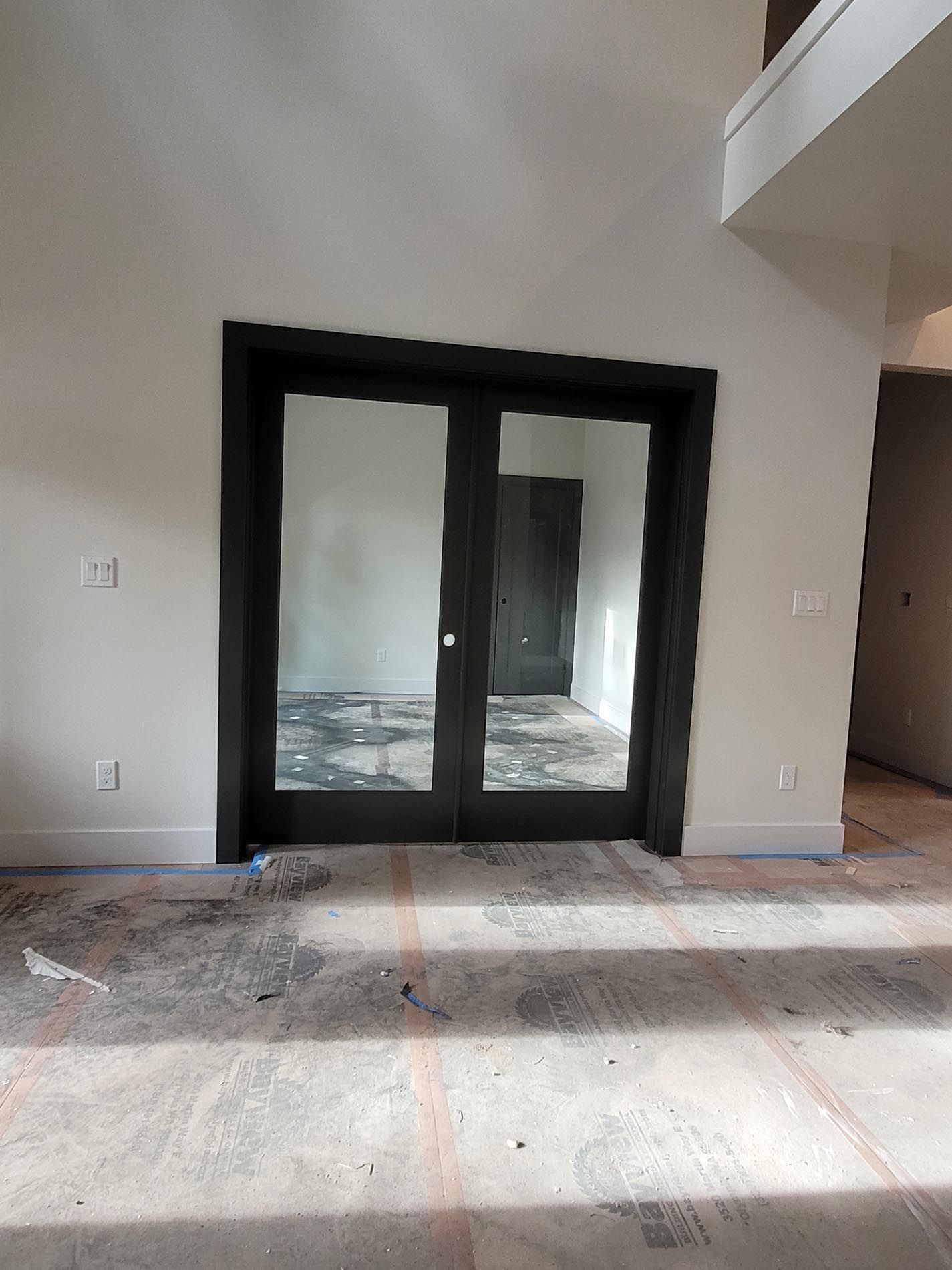 An empty room with a black door and a mirror