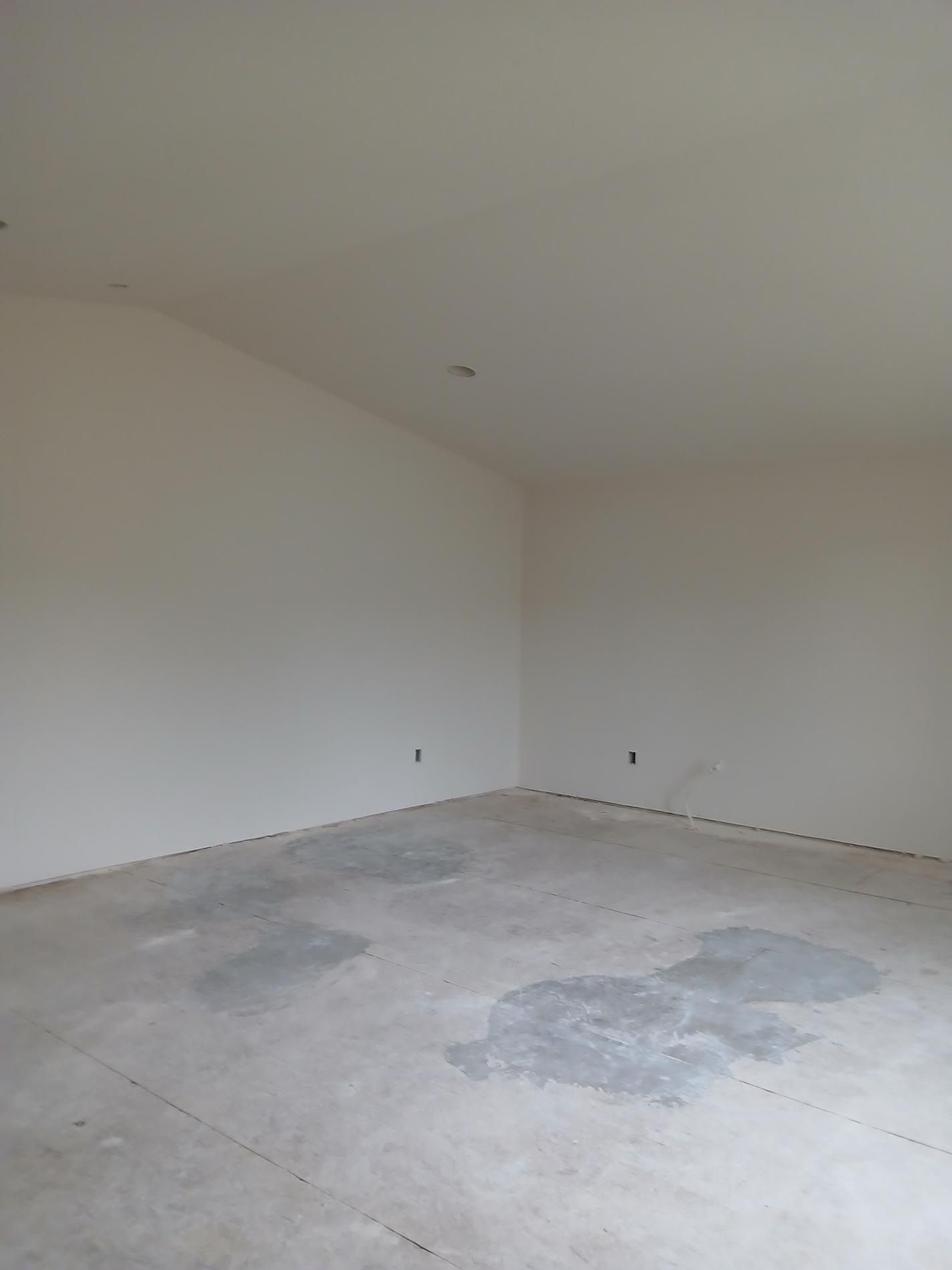 An empty room with white walls and a concrete floor