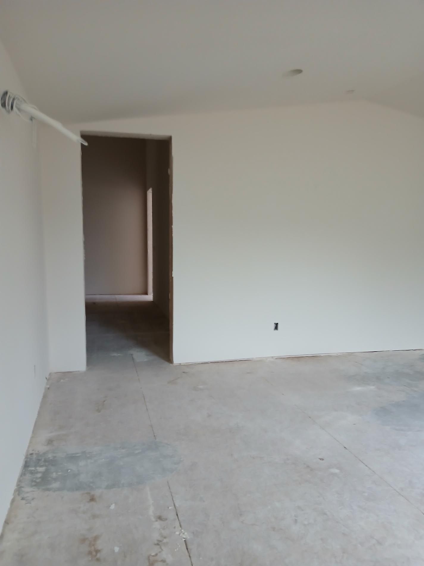 An empty room with white walls and a concrete floor