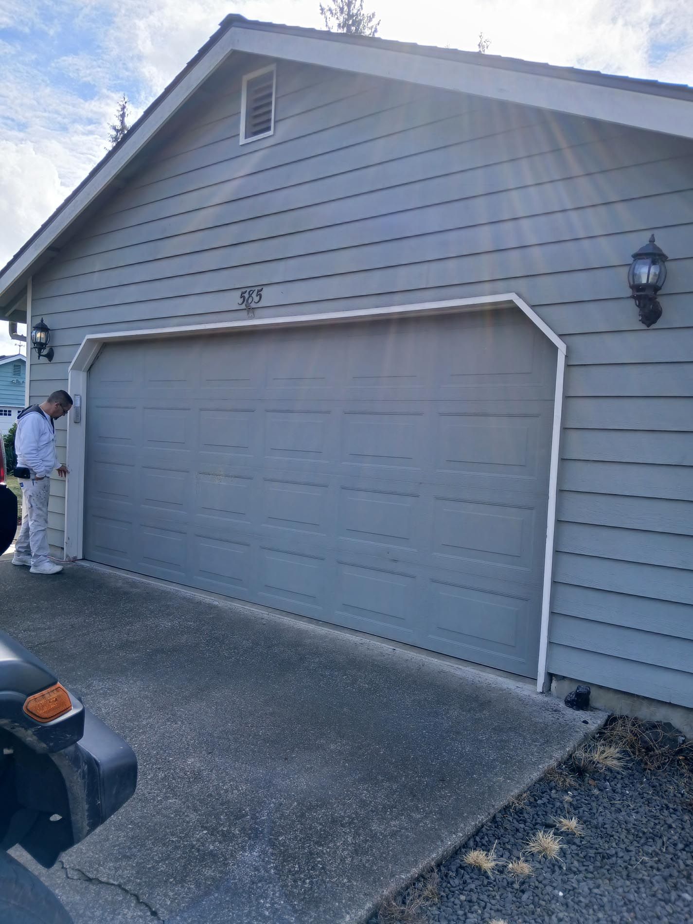 A man is painting the garage door of a house.
