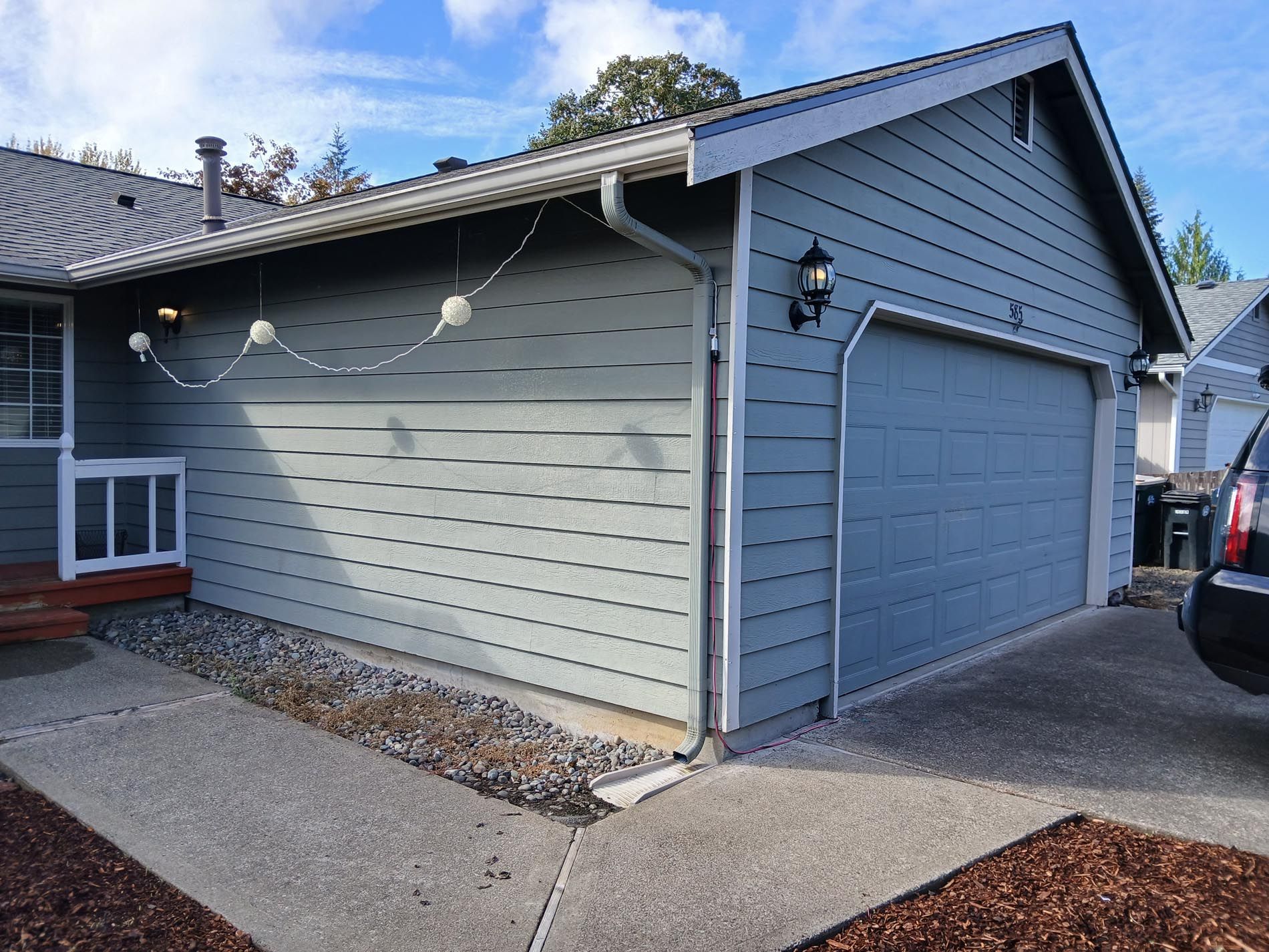 A car is parked in front of a house with a garage door