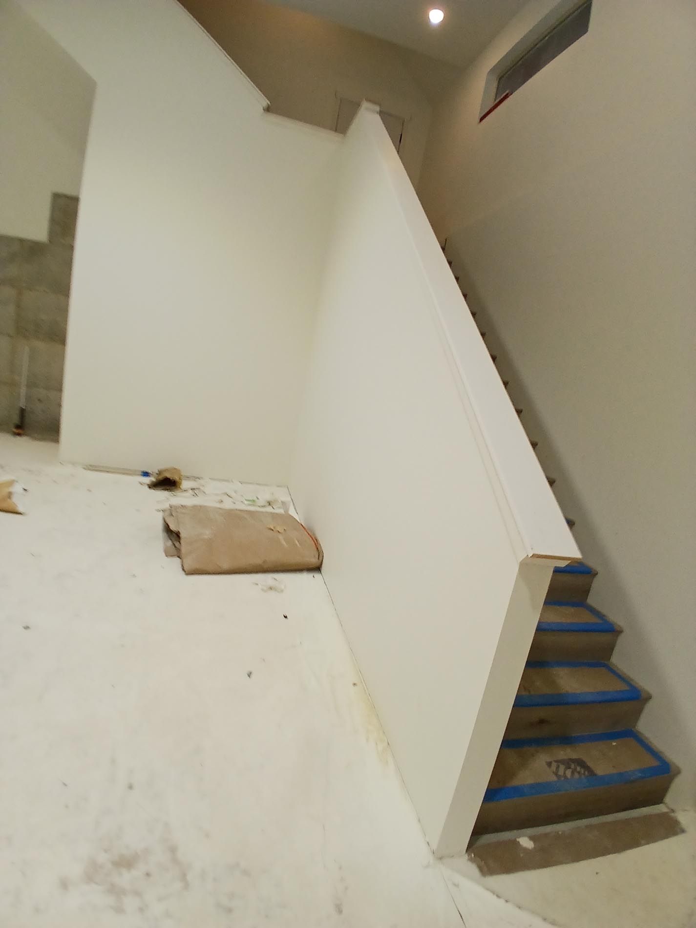A staircase with blue tape on the steps and a white wall.