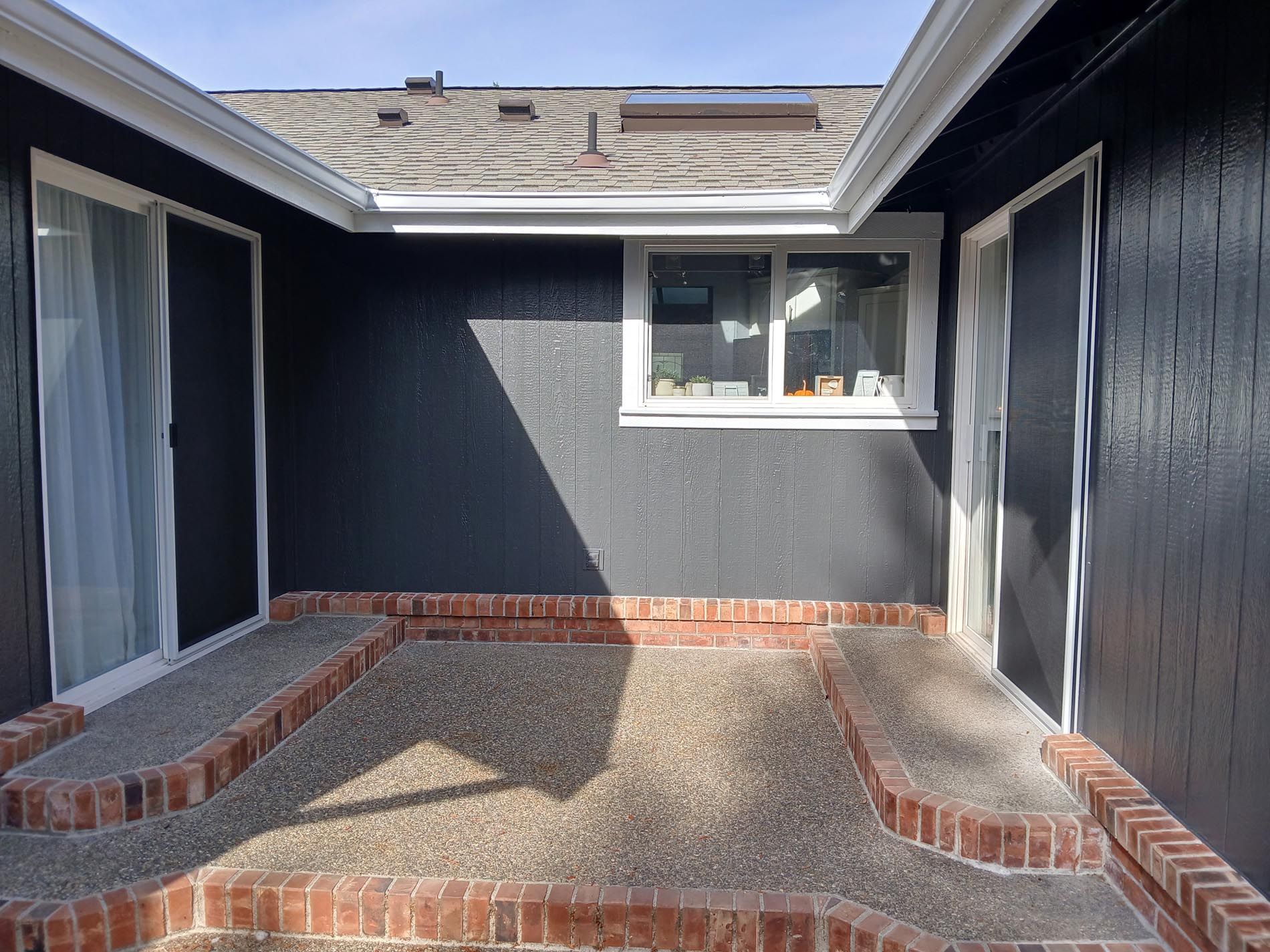 A black house with a brick walkway and a window