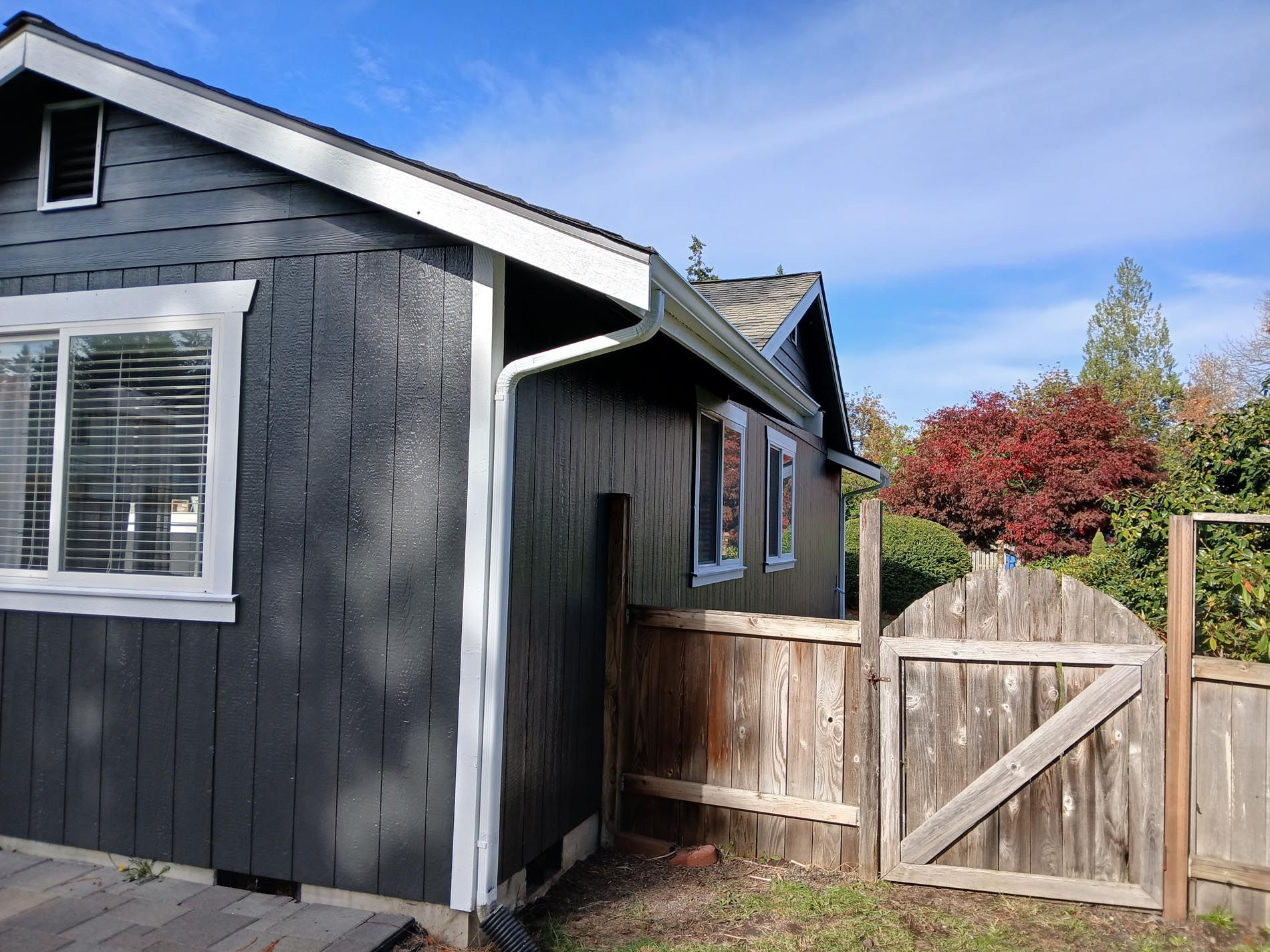 A small black house with a wooden fence in front of it.