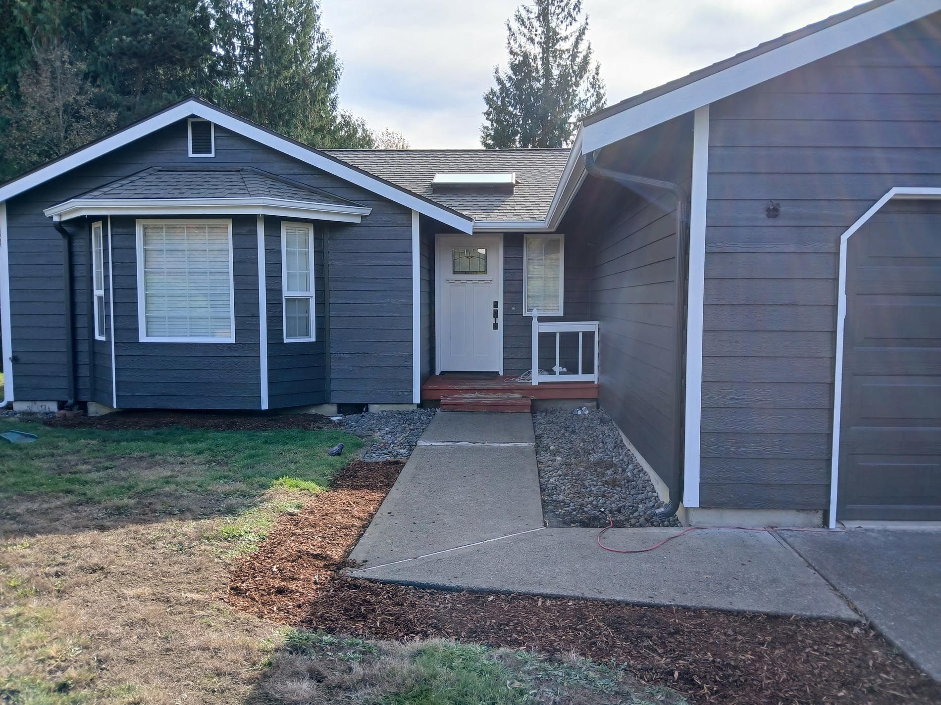 A gray house with a white door and a walkway leading to it
