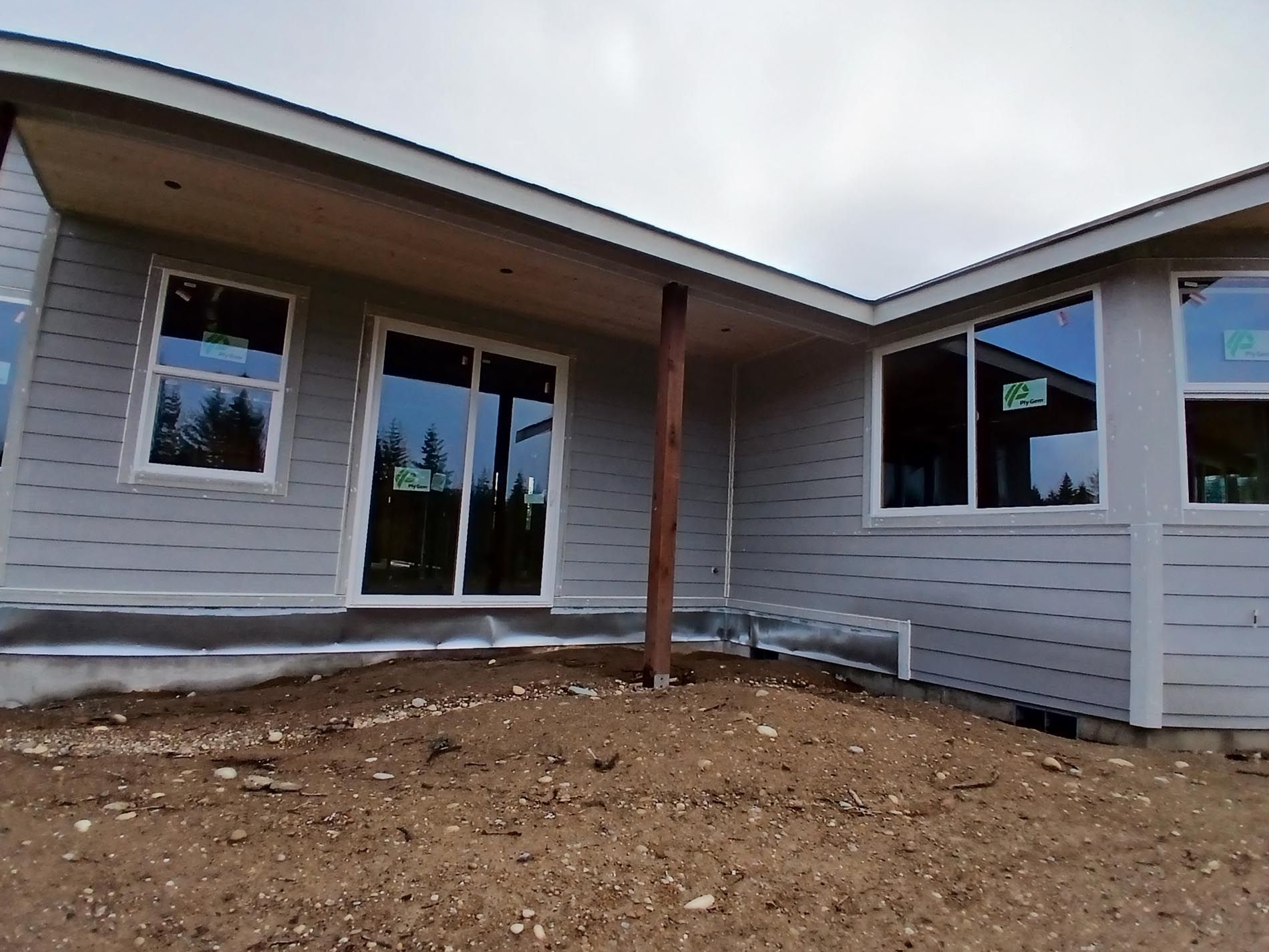 A house with a lot of windows is sitting on top of a dirt hill.