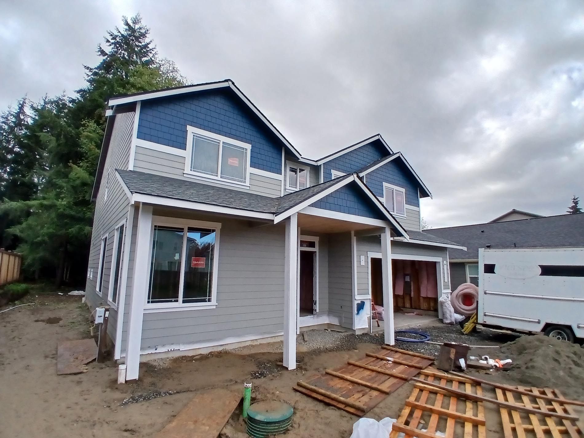 A blue and gray house is being built in a residential area.