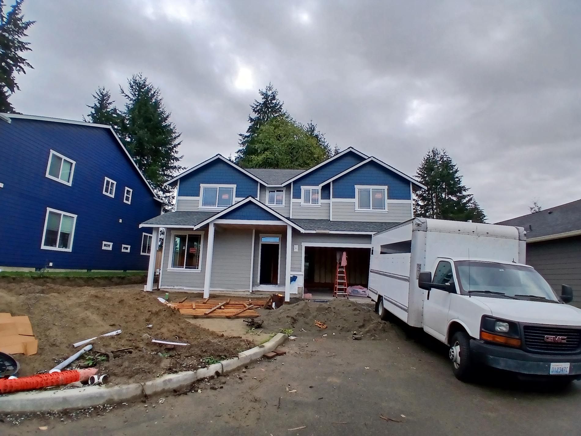 A white van is parked in front of a house under construction
