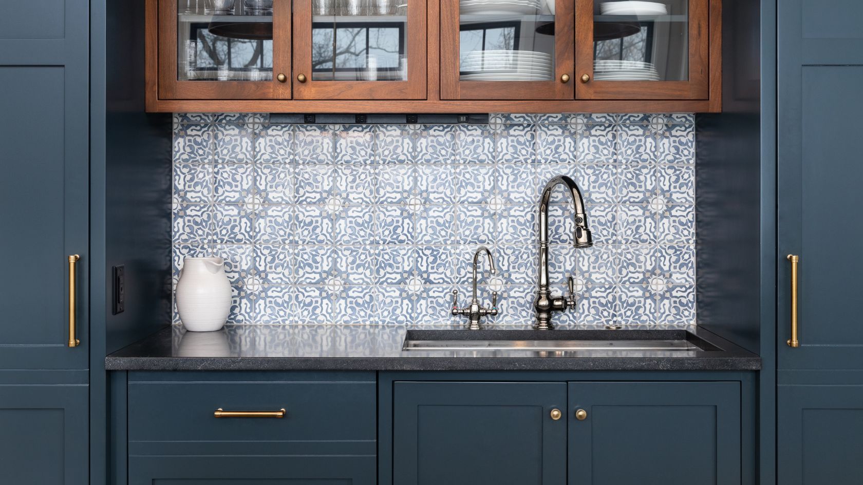 Dark blue kitchen with patterned tile backsplash, sink, and wooden cabinets.